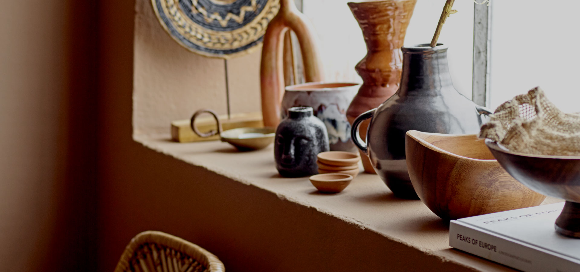 Na zdjęciu widoczny parapet z dekoracjami jesiennymi - ceramiczne dzbanki i wazony, drewniane miski i boho dodatki.