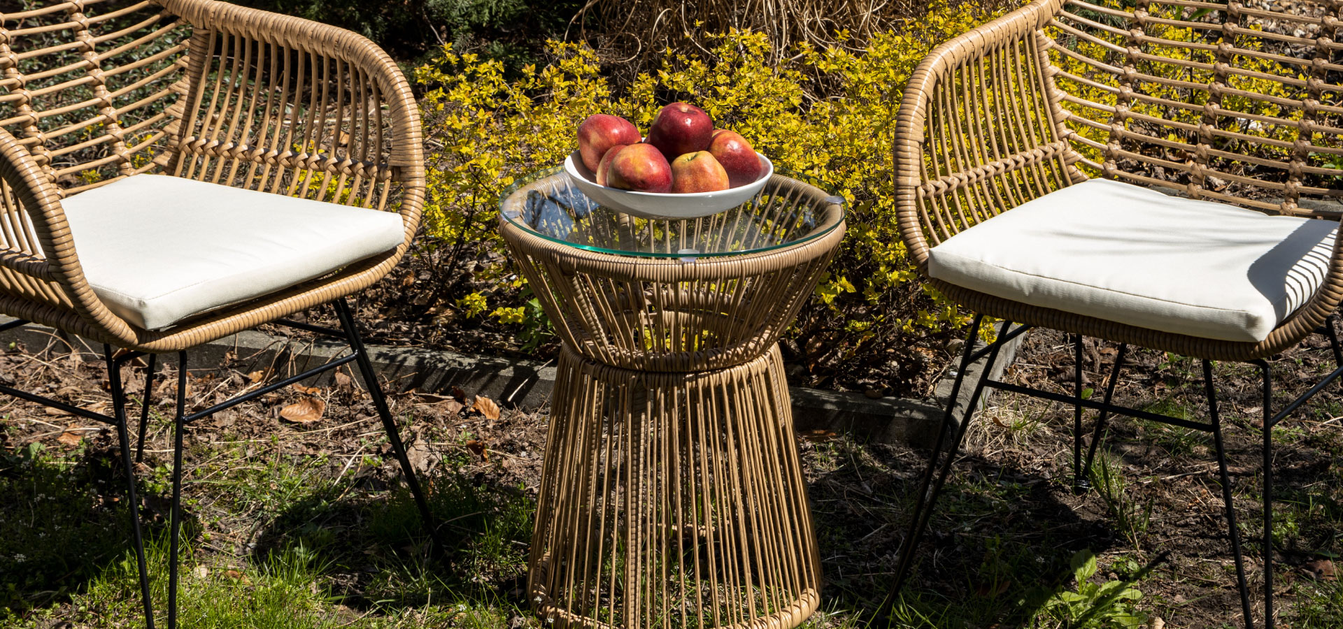 Zestaw balkonowy w stylu boho z dwoma krzesłami i stolikiem. Na stoliku stoi miska z jabłkami.