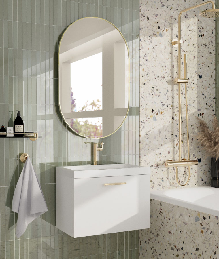 Wizualizacja łazienki z białą szafką pod umywalkę ze złotym uchwytem. Nad umywalką zawieszone owalne lustro w cienkiej, złotej ramie. W tle płytki w lastryko oraz kontrastujące drobne płytki w odcieniu szałwiowym.