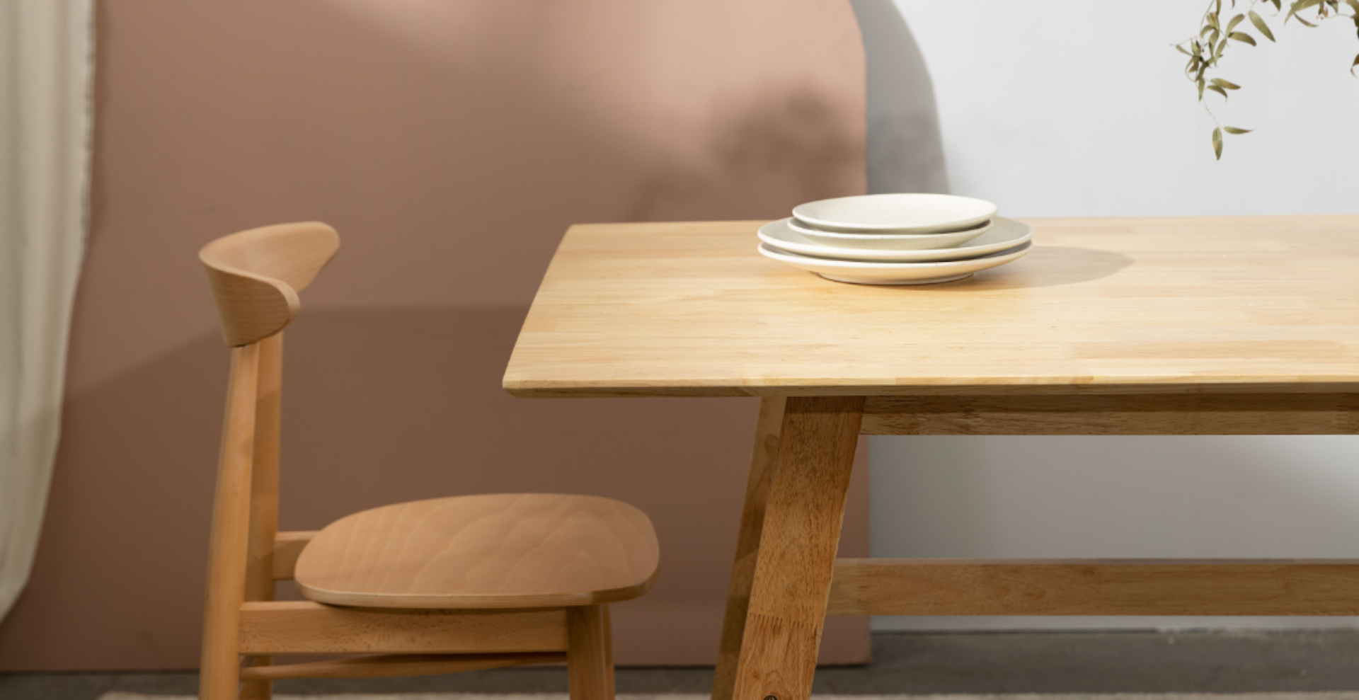 Stół oraz krzesło w kolorze jasnego drewna. na stole ułożone talerze w beżowym kolorze.