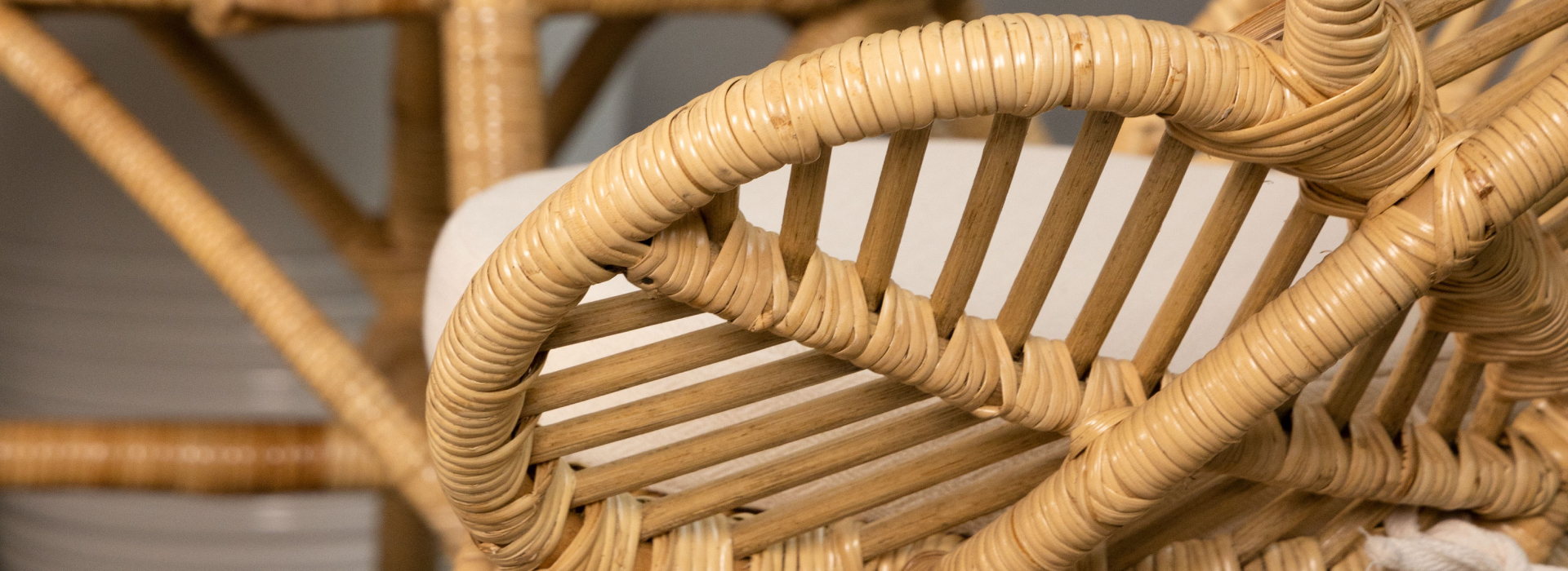 Zbliżenie na bok plecionego fotela wykonanego w całości z naturalnego rattanu.
