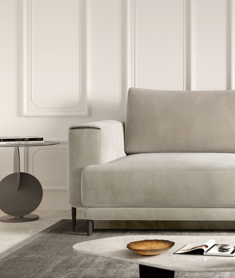 Jasnobeżowa sofa o prostym kształcie na czarnych nóżkach i szerokich podłokietnikach, po prawej stronie designerski stolik kawowy.