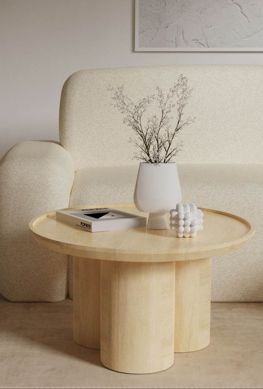 Drewniany stolik kawowy na trzech walcowatych nogach złączonych ze sobą, na stoliku dekoracje, w tle beżowa sofa o obłym kształcie.