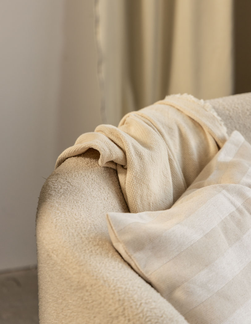 Beżowa sofa dwuosobowa Organica w tkaninie boucle, całość na złotej podstawie