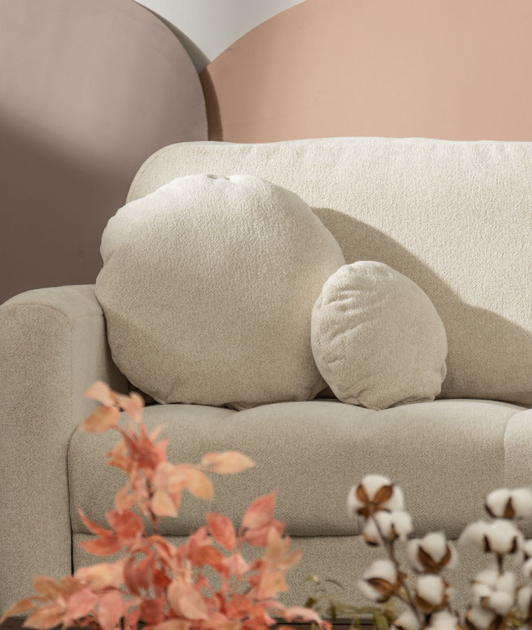 Beżowa sofa i fotel w tkaninie boucle w aranżacji boho, z przodu złoty stolik z marmurowym blatem