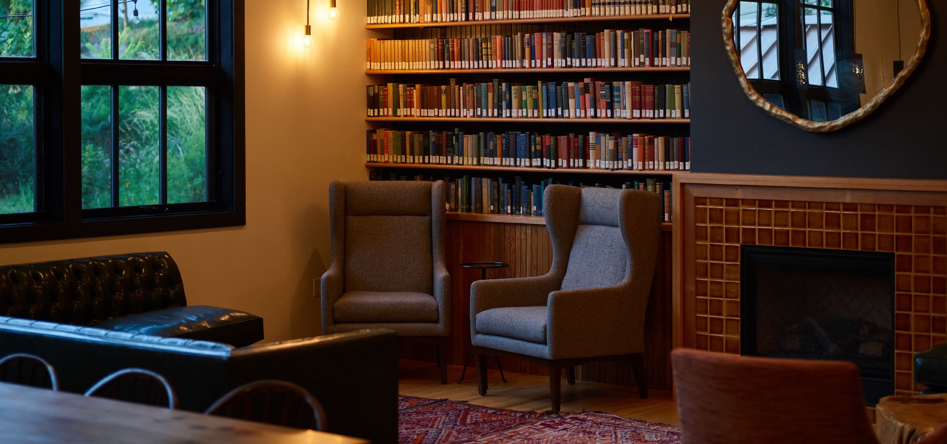 Gabinet z dużą biblioteczką wypełnioną książkami. Pod biblioteczką widoczne dwa krzesła i kominek