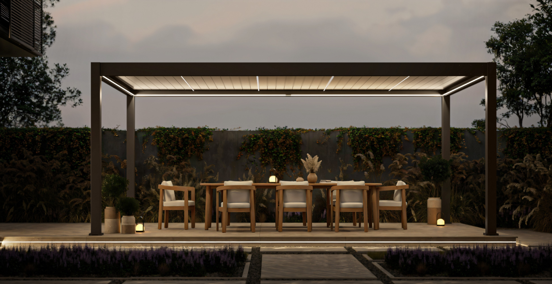 Nowoczesna pergola ogrodowa z wbudowanym oświetleniem LED, pod którą stoi drewniany stół z tapicerowanymi krzesłami; nastrojowa aranżacja tarasu o zmierzchu, z roślinnością i subtelnymi lampionami w tle.